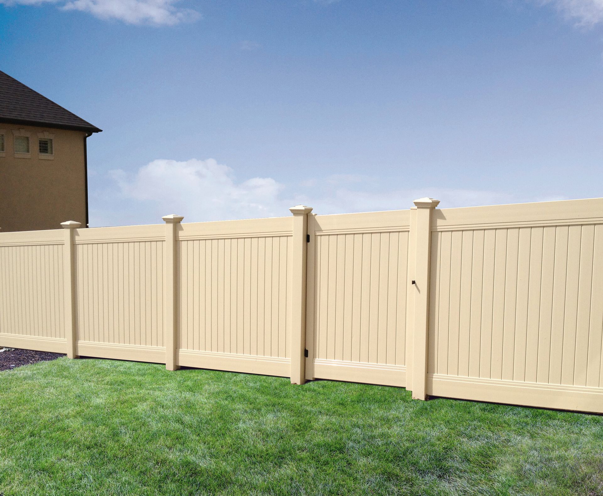 A white fence surrounds a lush green yard with a house in the background.