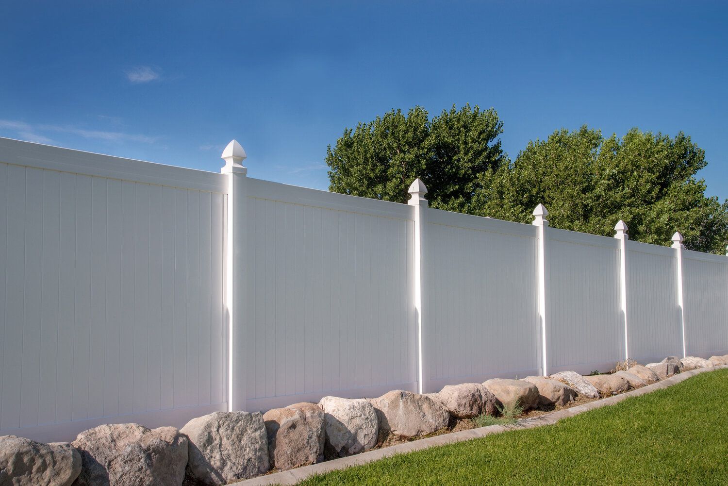 A white fence is surrounded by rocks and grass.