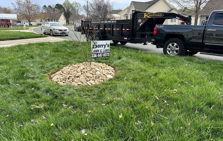 A black truck is parked in the grass next to a pile of wood chips.