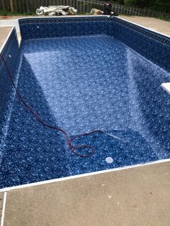 Empty, dark blue swimming pool with white coping, concrete deck.