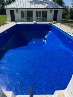 Empty blue swimming pool with white building in the background.