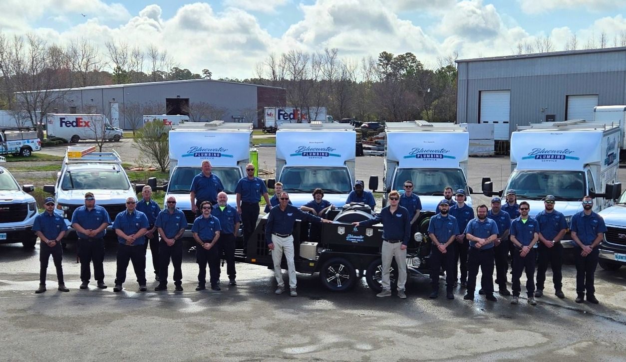 Bluewater company team posing in front of their van; blue shirts, smiles, inside a garage.