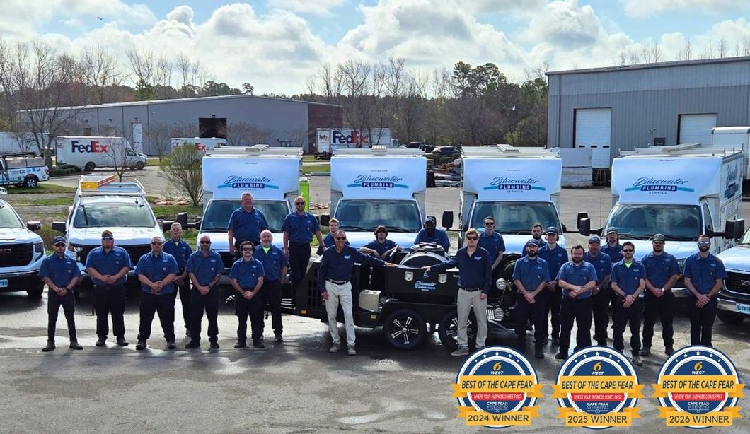 Group of uniformed workers posing in front of white service trucks in an industrial lot