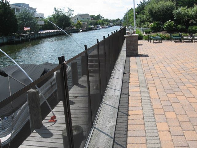 Riverfront walkway with black railing beside a canal and brick pavement on a sunny day