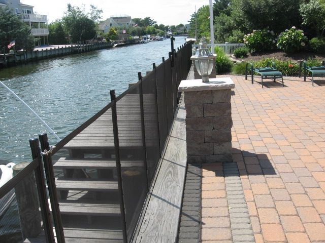Canal-side walkway with a metal stairway descending to the water beside a brick patio