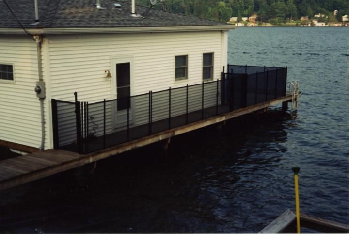 Docked boathouse with black railing beside choppy water at the shoreline