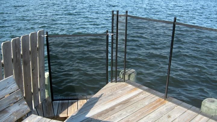 Wooden dock steps descending into blue water with metal railings on each side