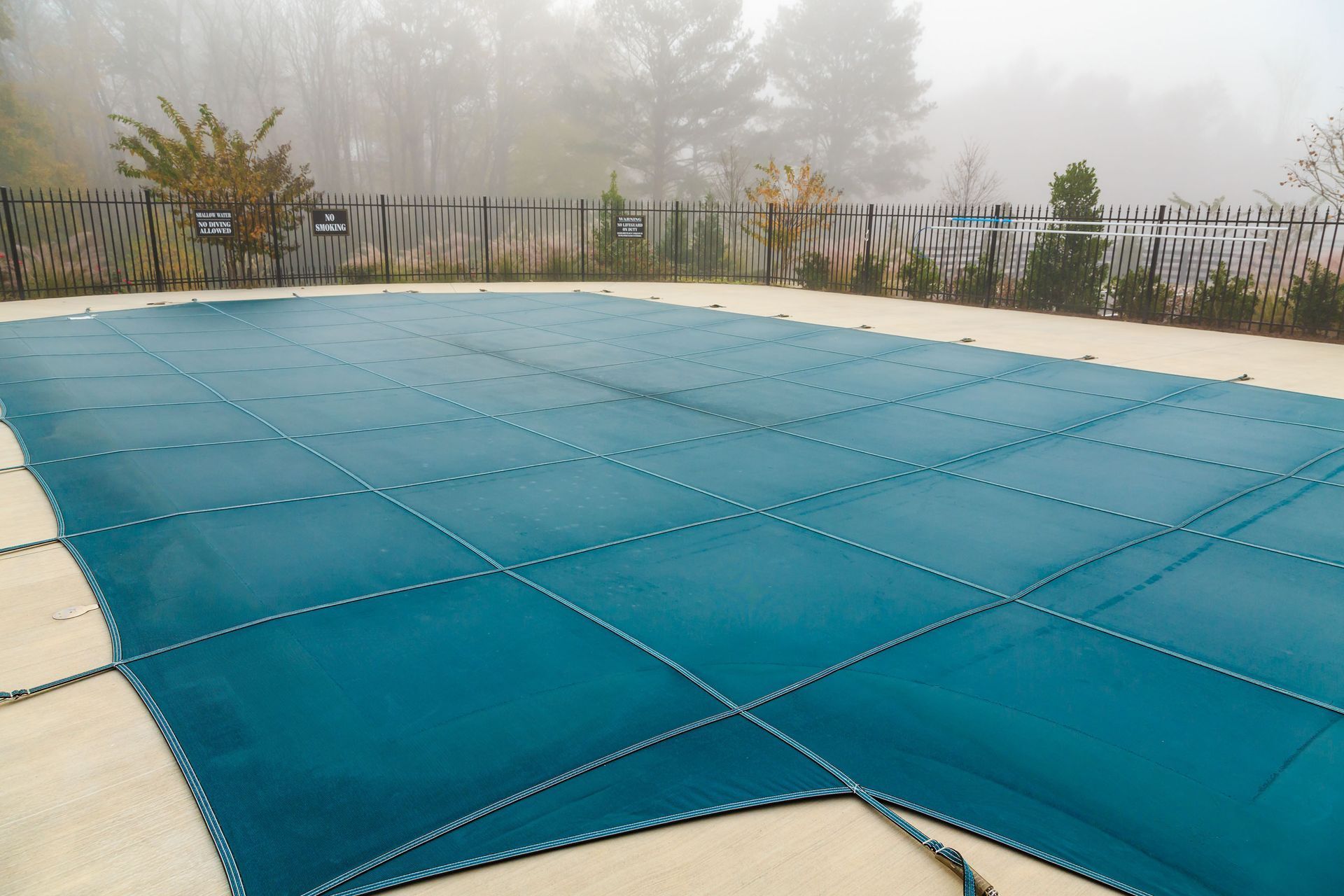 Blue pool cover over an outdoor swimming pool on a foggy morning