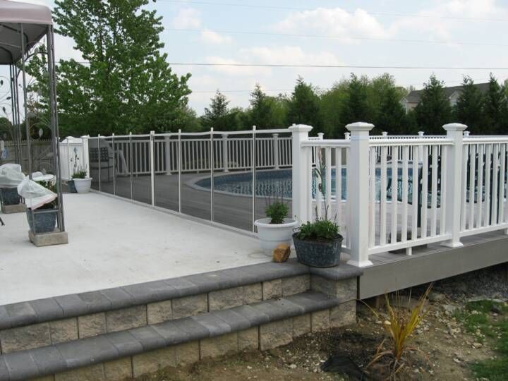 White fenced backyard patio with steps, potted plants, and an in-ground pool beyond the railing