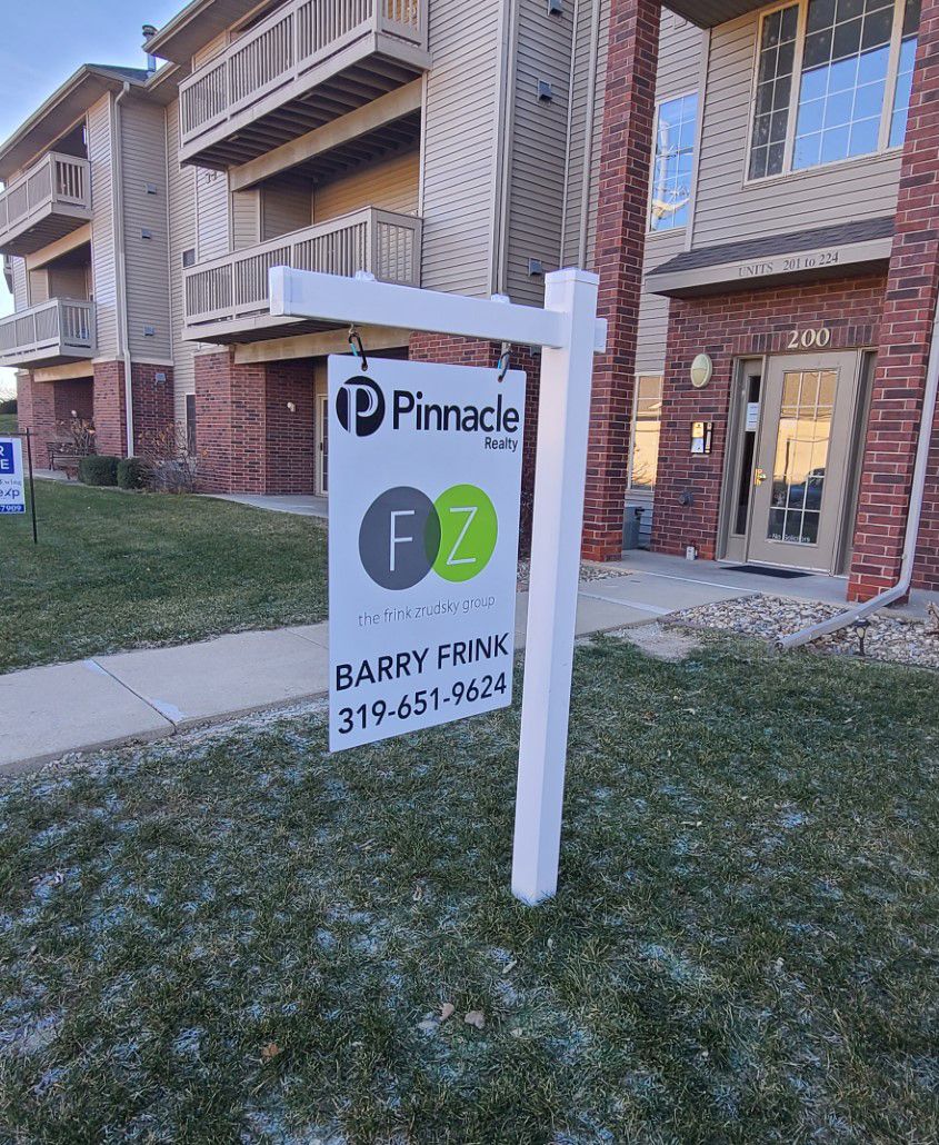 A for sale sign in front of a brick building.