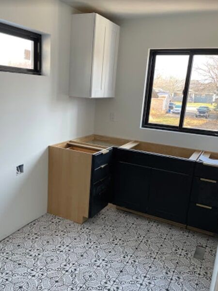 a kitchen under construction with black cabinets and a window