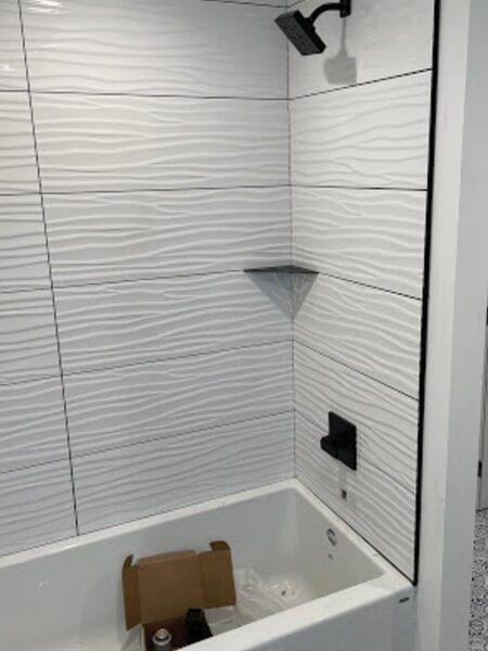 a bathtub in a bathroom with white tiles and a shower