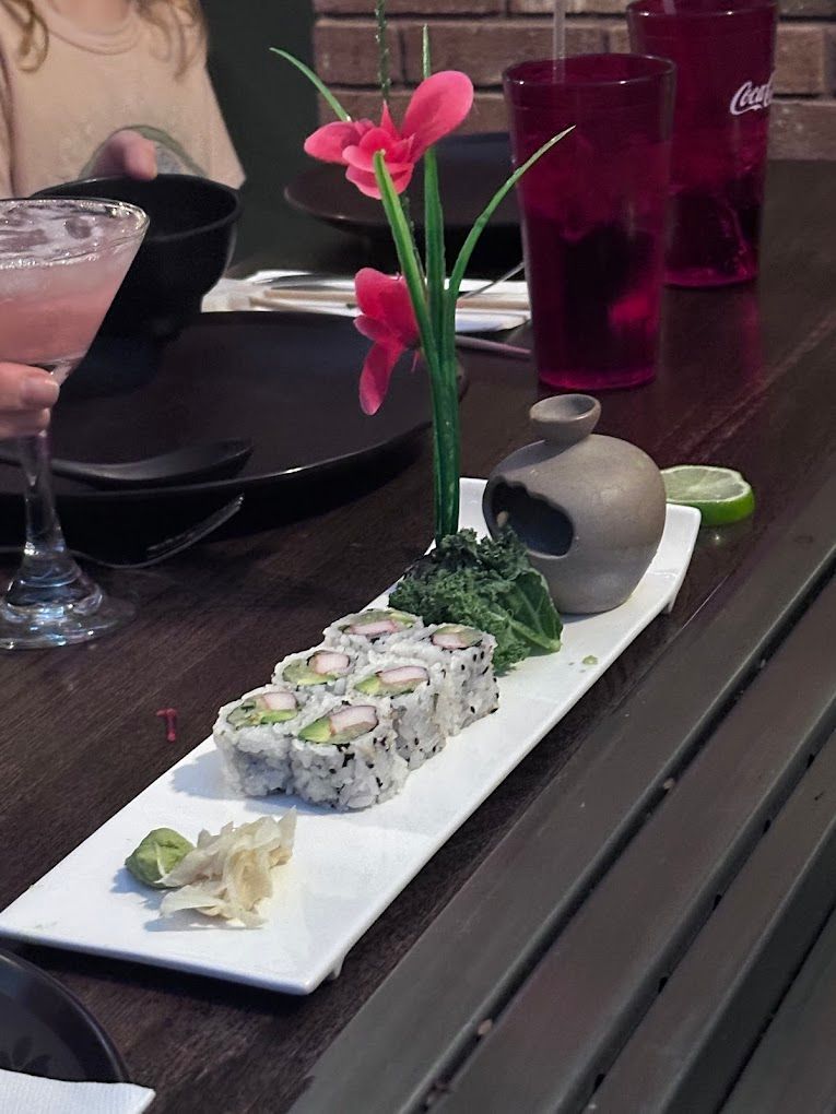 A plate of sushi and a vase of flowers on a table