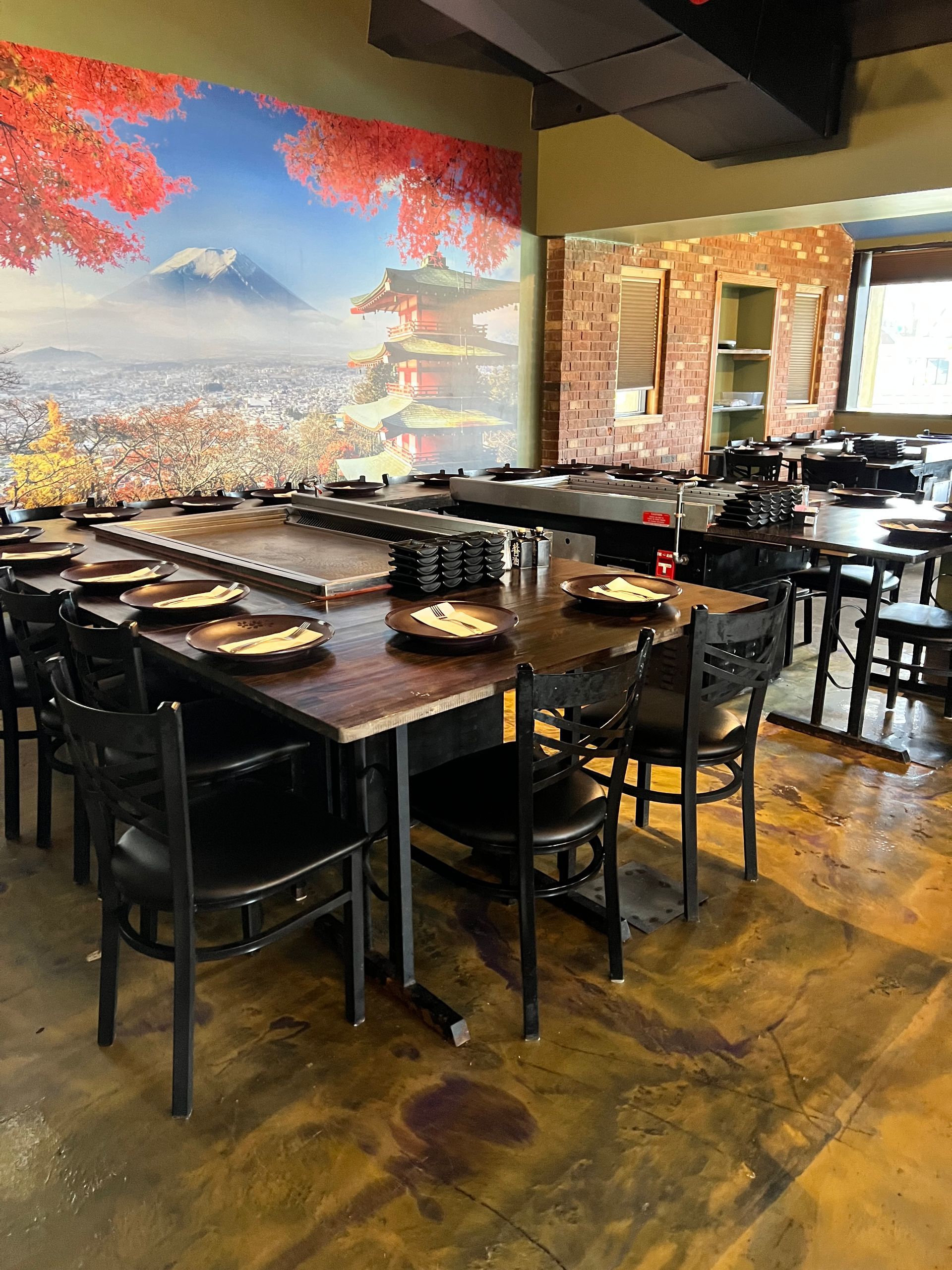 A restaurant with tables and chairs and a large picture on the wall.