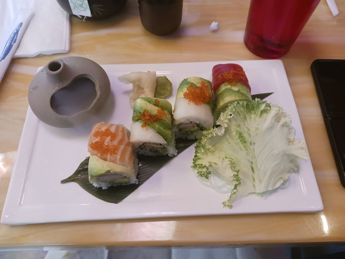 A white plate topped with sushi and lettuce on a table