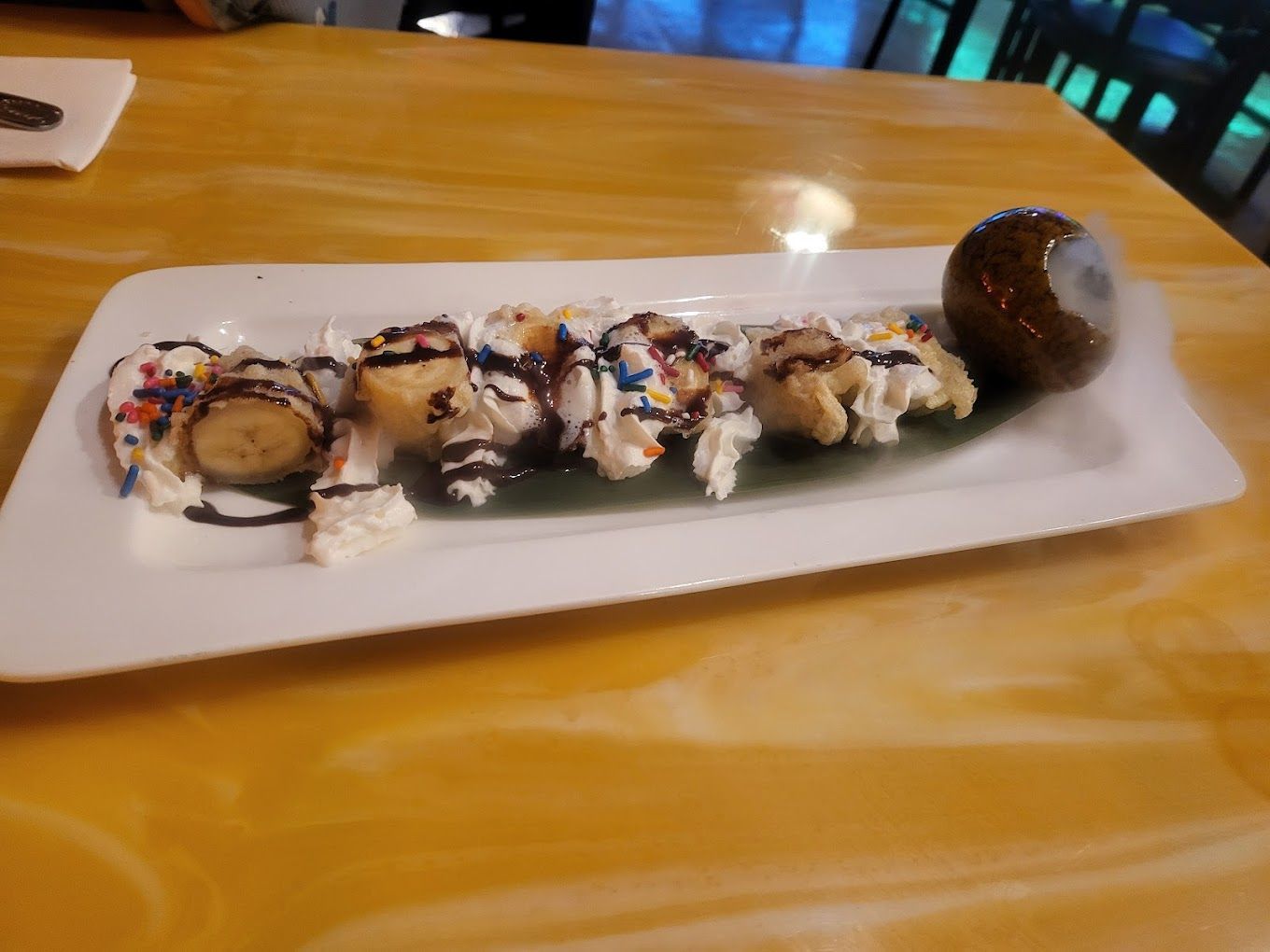 A white plate topped with bananas and ice cream on a table