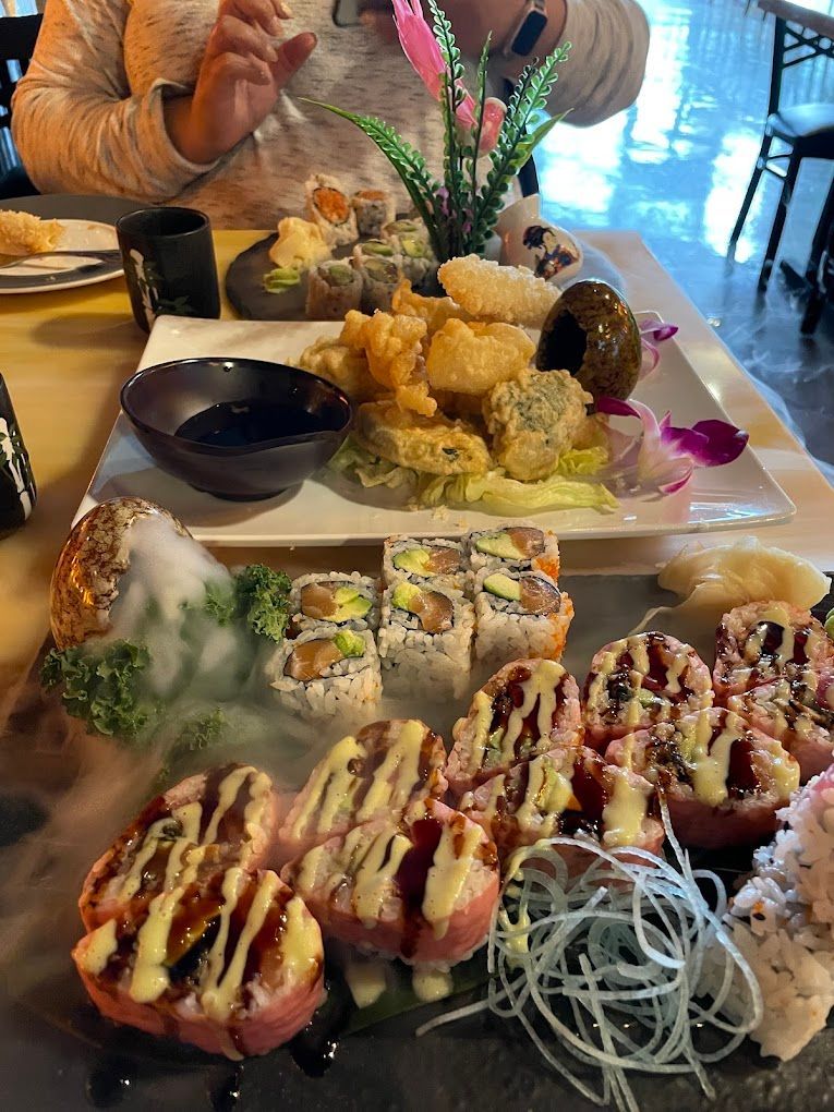 A person is sitting at a table with a plate of sushi on it.
