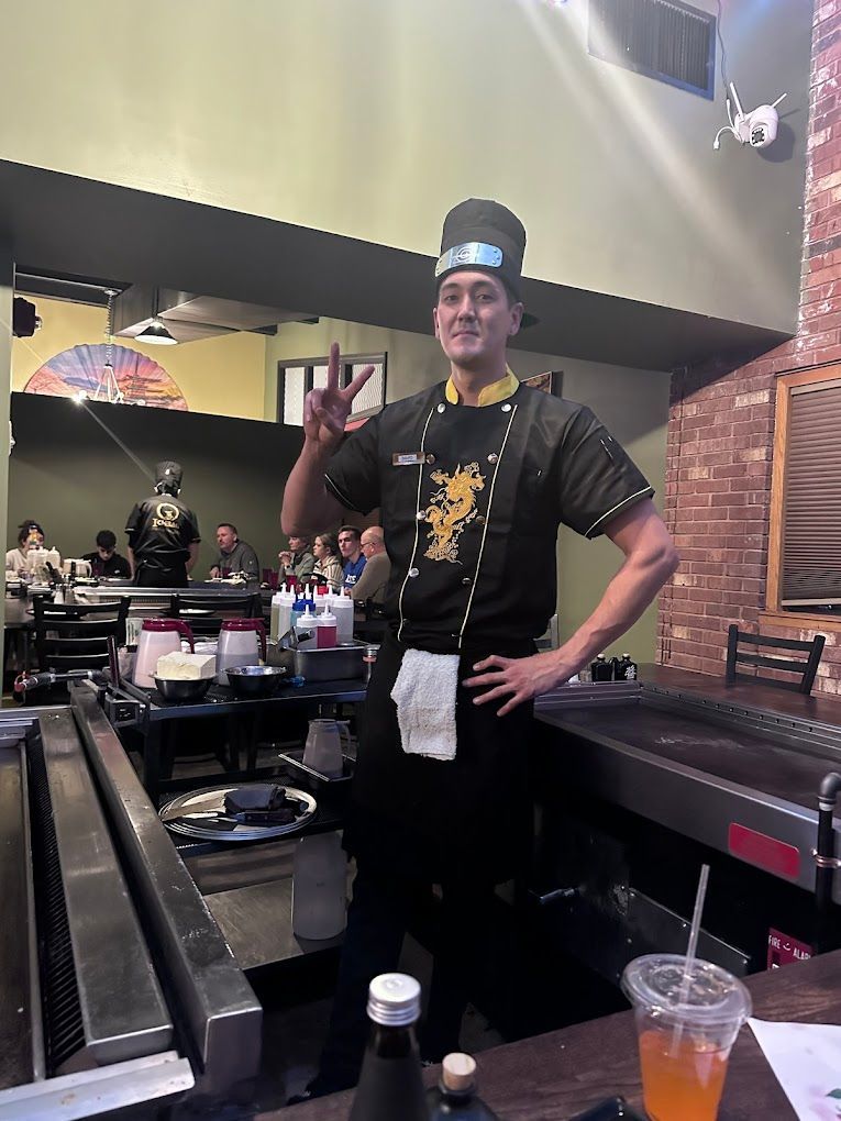 A man in a chef 's uniform is standing in a restaurant.