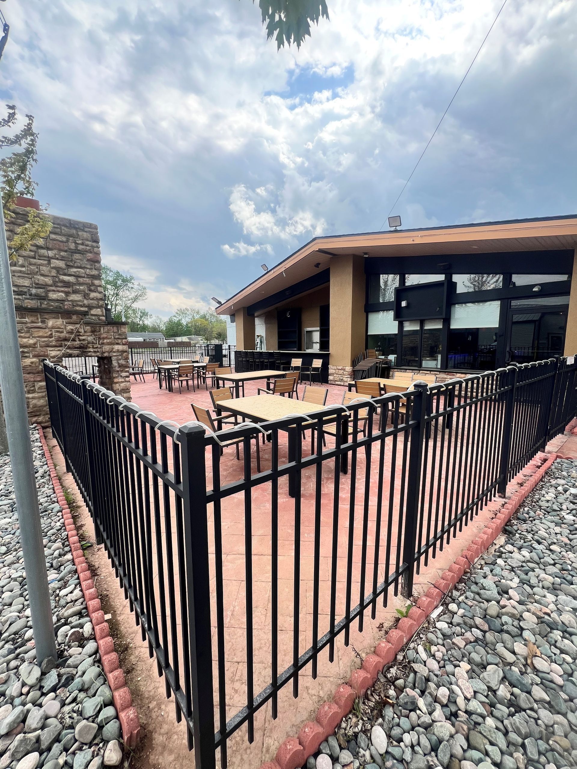 A restaurant with tables and chairs behind a fence.