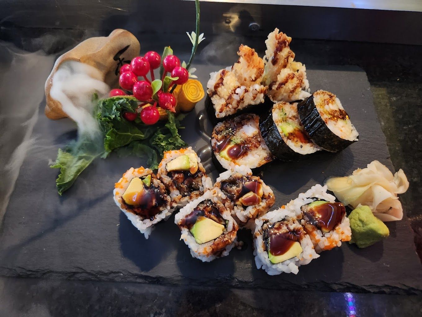 A tray of sushi and vegetables on a table with smoke coming out of it.