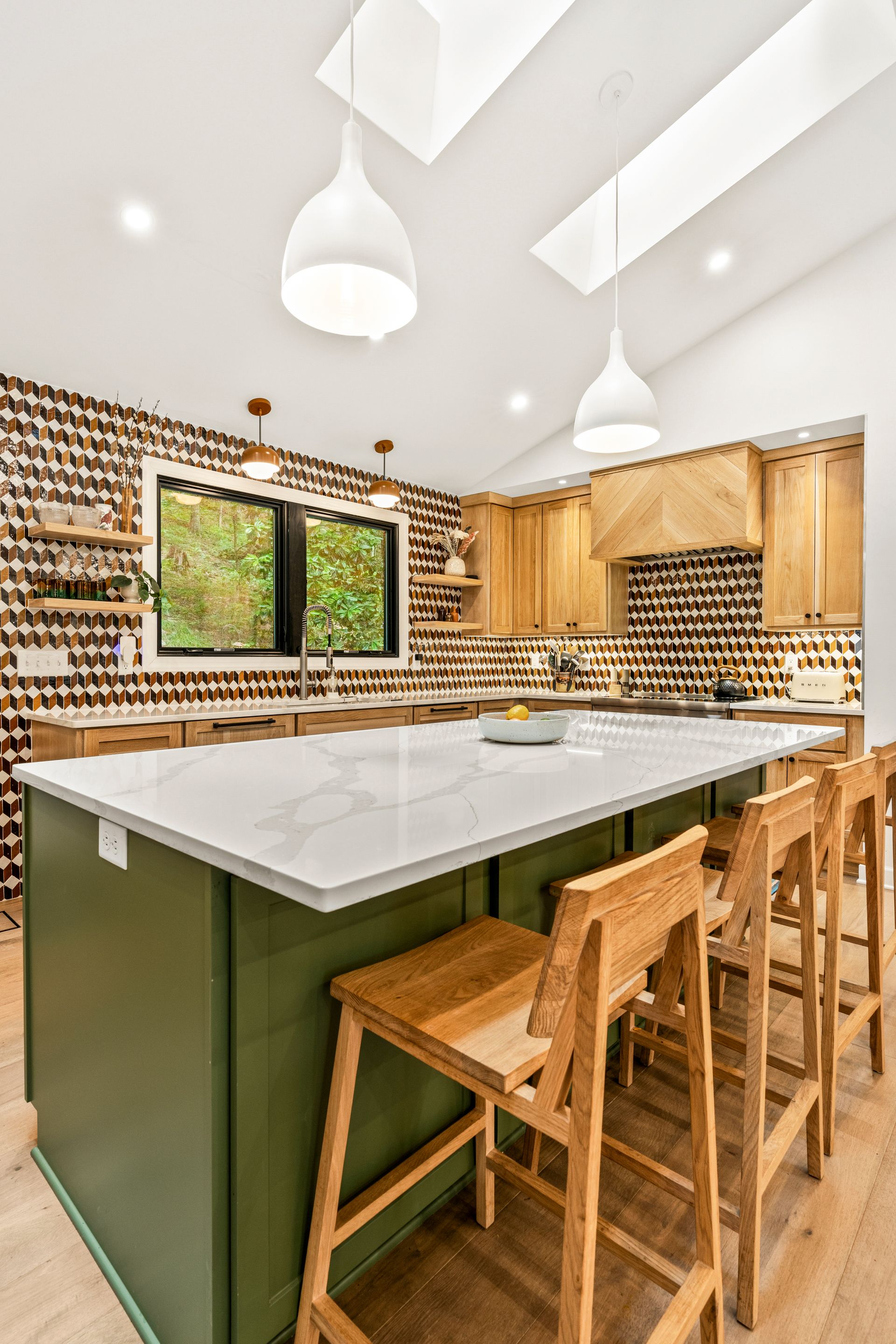 Modern kitchen with green island, white countertops, wooden stools, and mosaic backsplash.