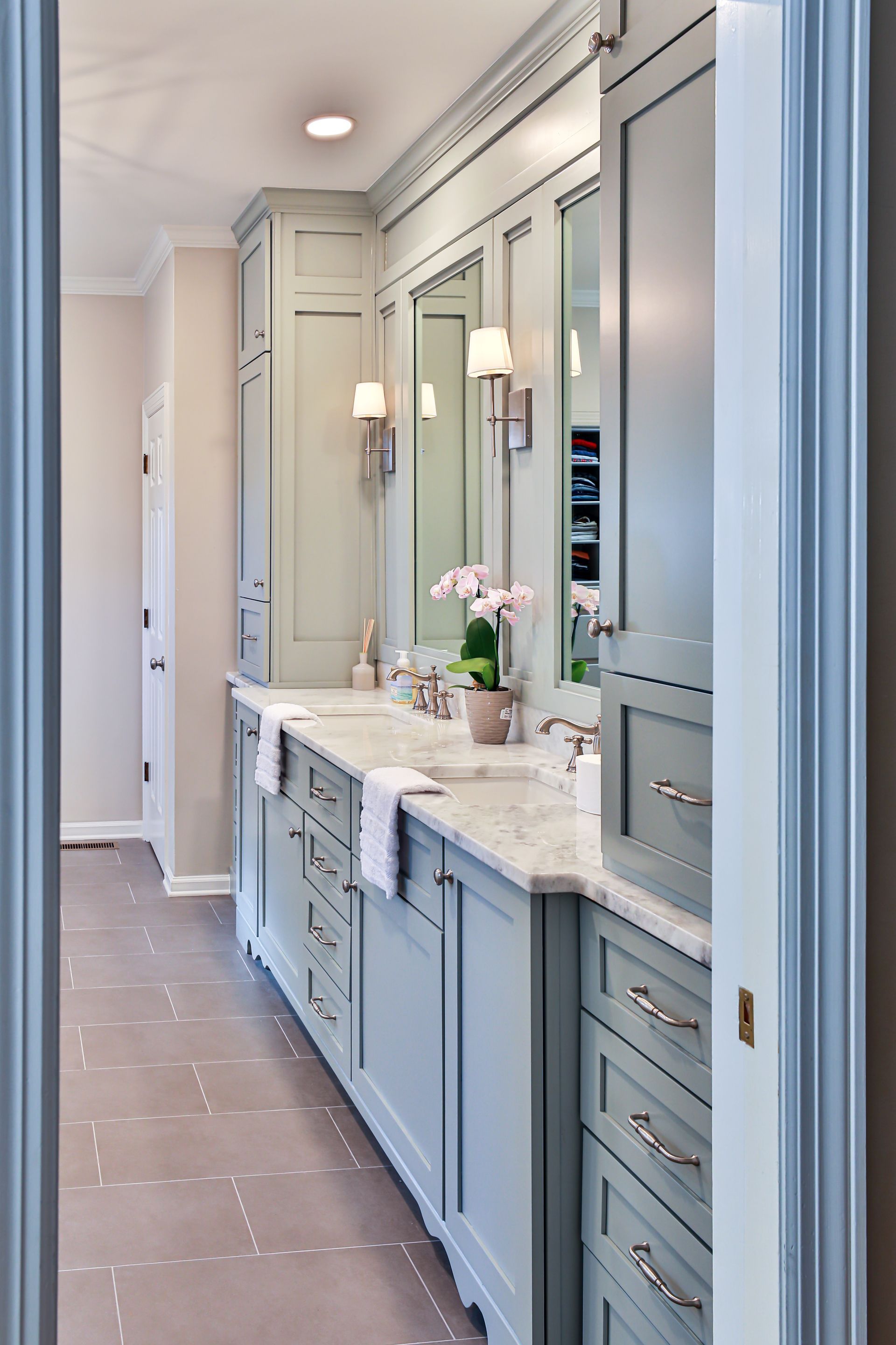 Light blue bathroom vanity with double sinks and mirrors, soft lighting.