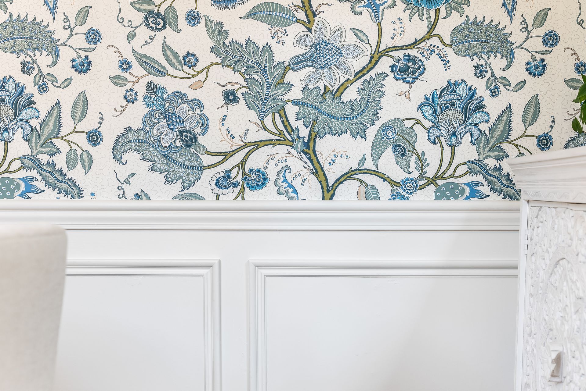 Blue floral wallpaper above white wainscoting; section of a wall.