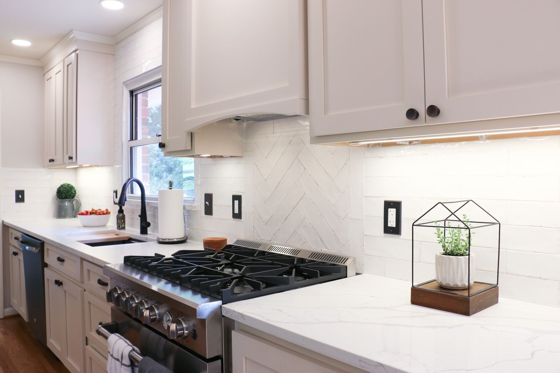Modern white kitchen with a stainless steel stove and white countertops.