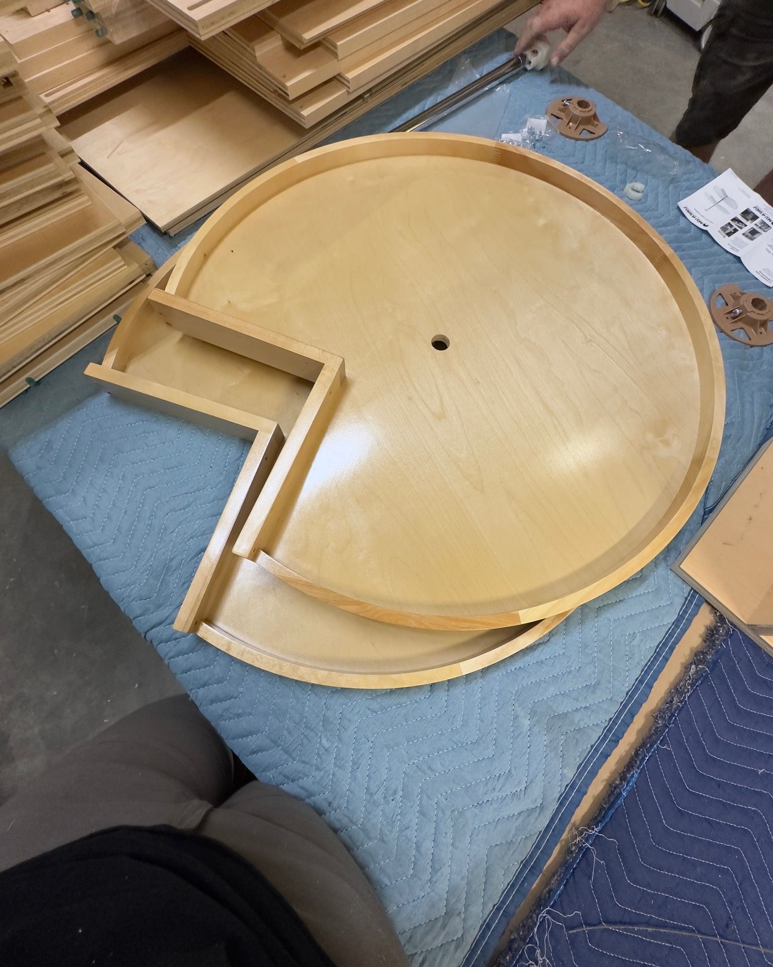 Circular wooden cabinet lazy susan parts on a blue surface.