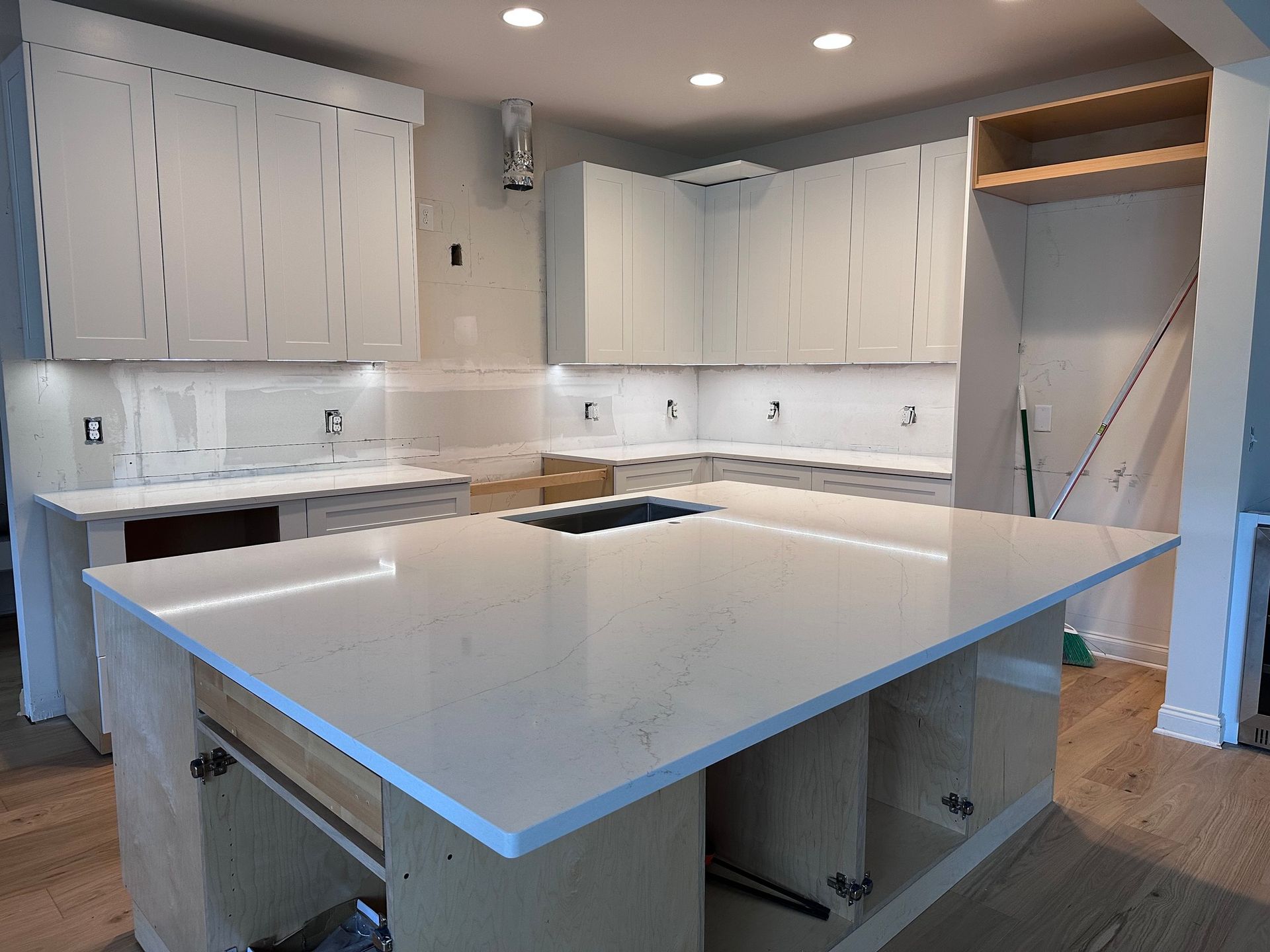White kitchen with island, cabinets, countertops, and unfinished appliance space.