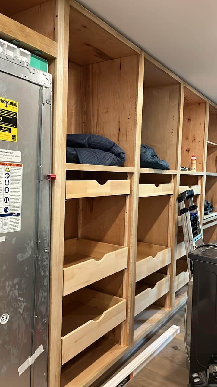 Wooden shelves with drawers built around a utility unit in a room.
