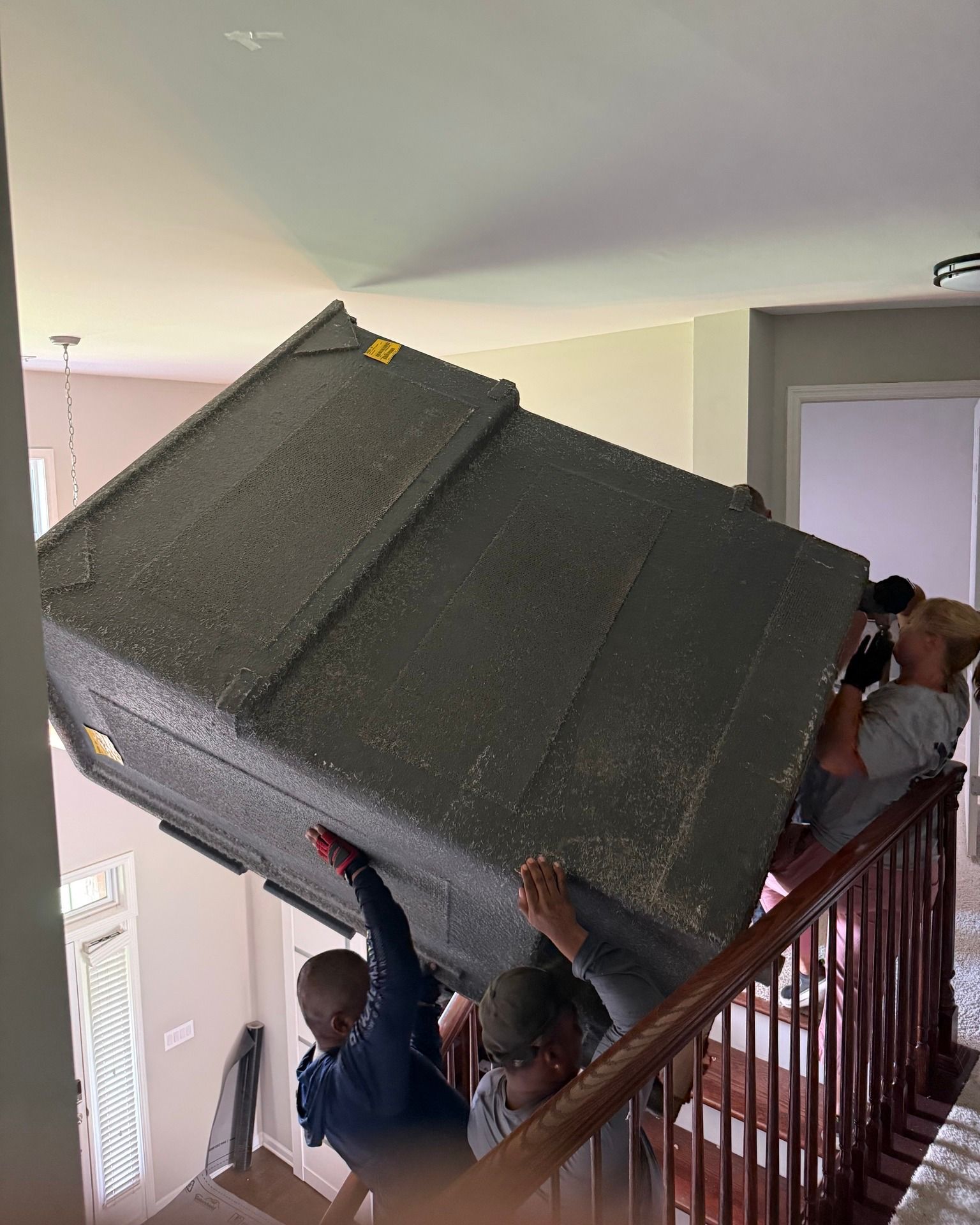 People carrying a large, dark box up a staircase.