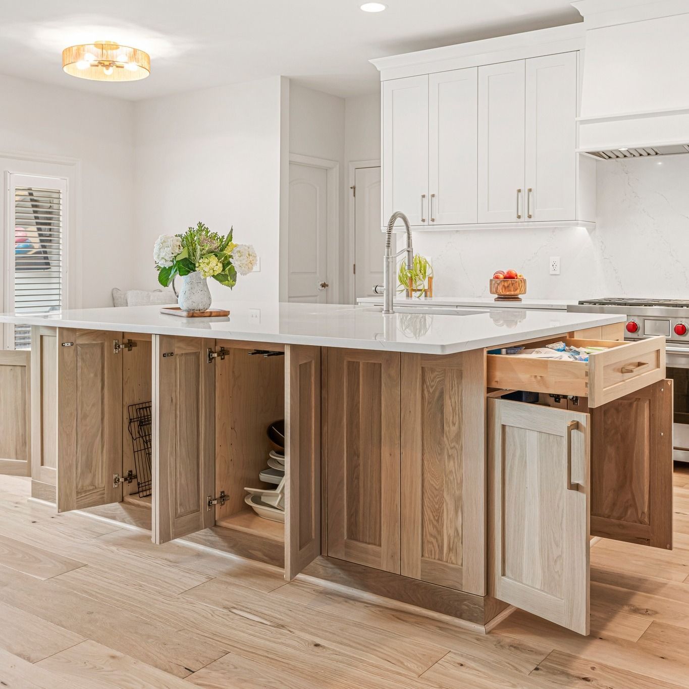 Kitchen island with open cabinets and drawers, showcasing storage options. Light wood and white, modern design.