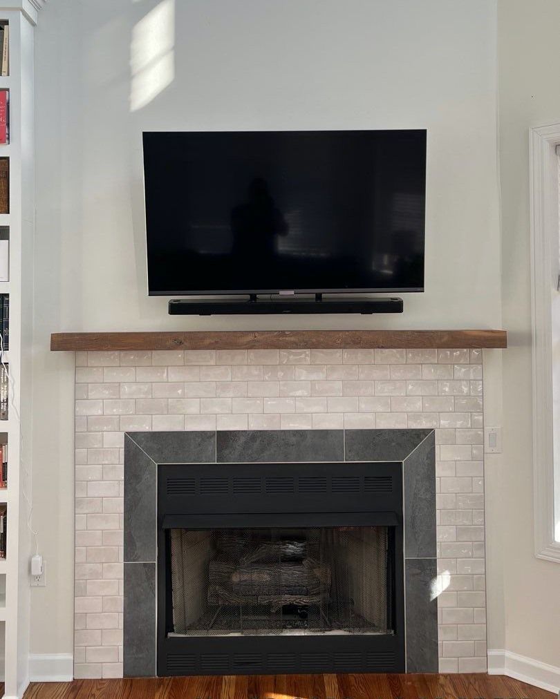 Fireplace with TV mounted above, a soundbar, and a wooden mantel. White brick with dark gray accents.