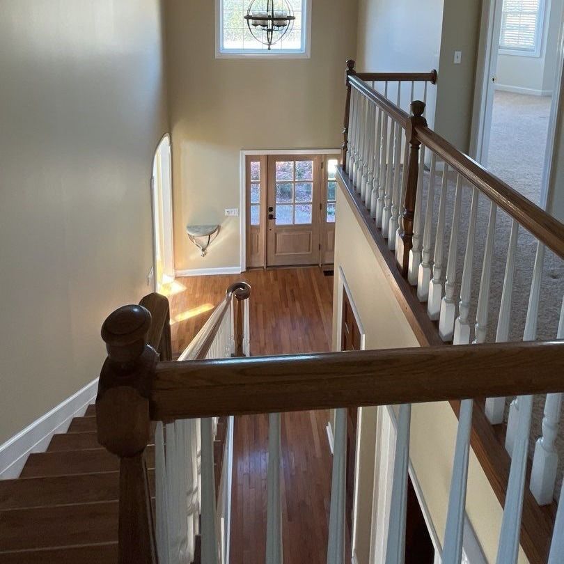 Overhead view of a two-story entry with wooden stairs, railing, and doorway.
