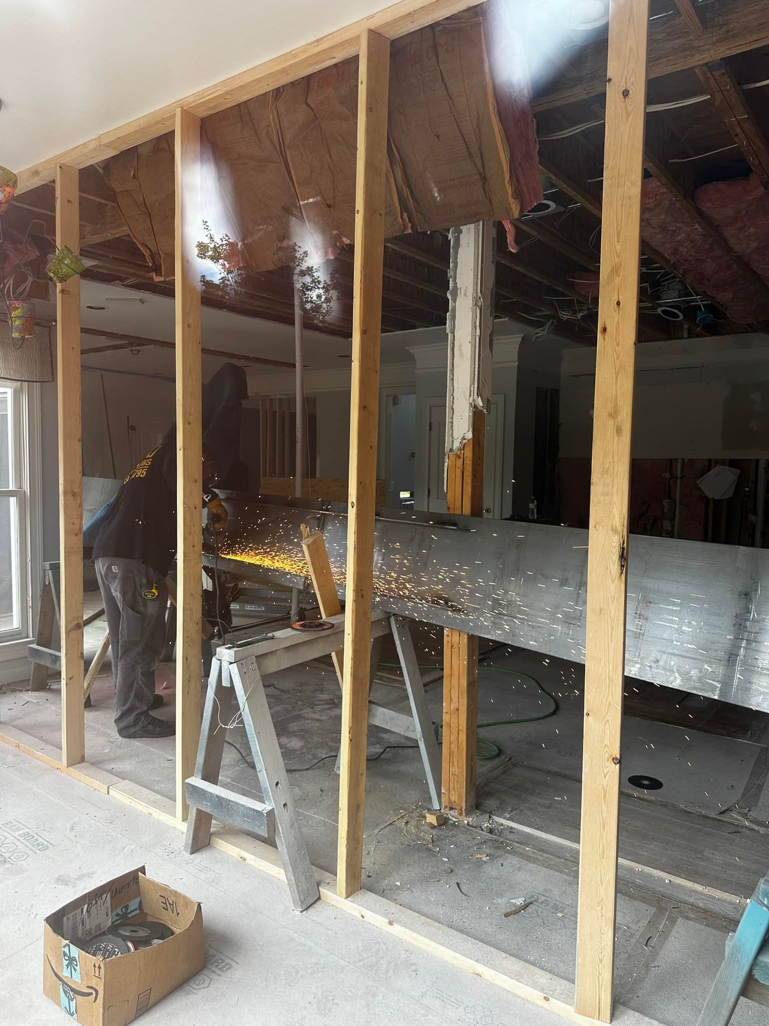 Person cutting metal with sparks flying, inside a room with wooden studs.