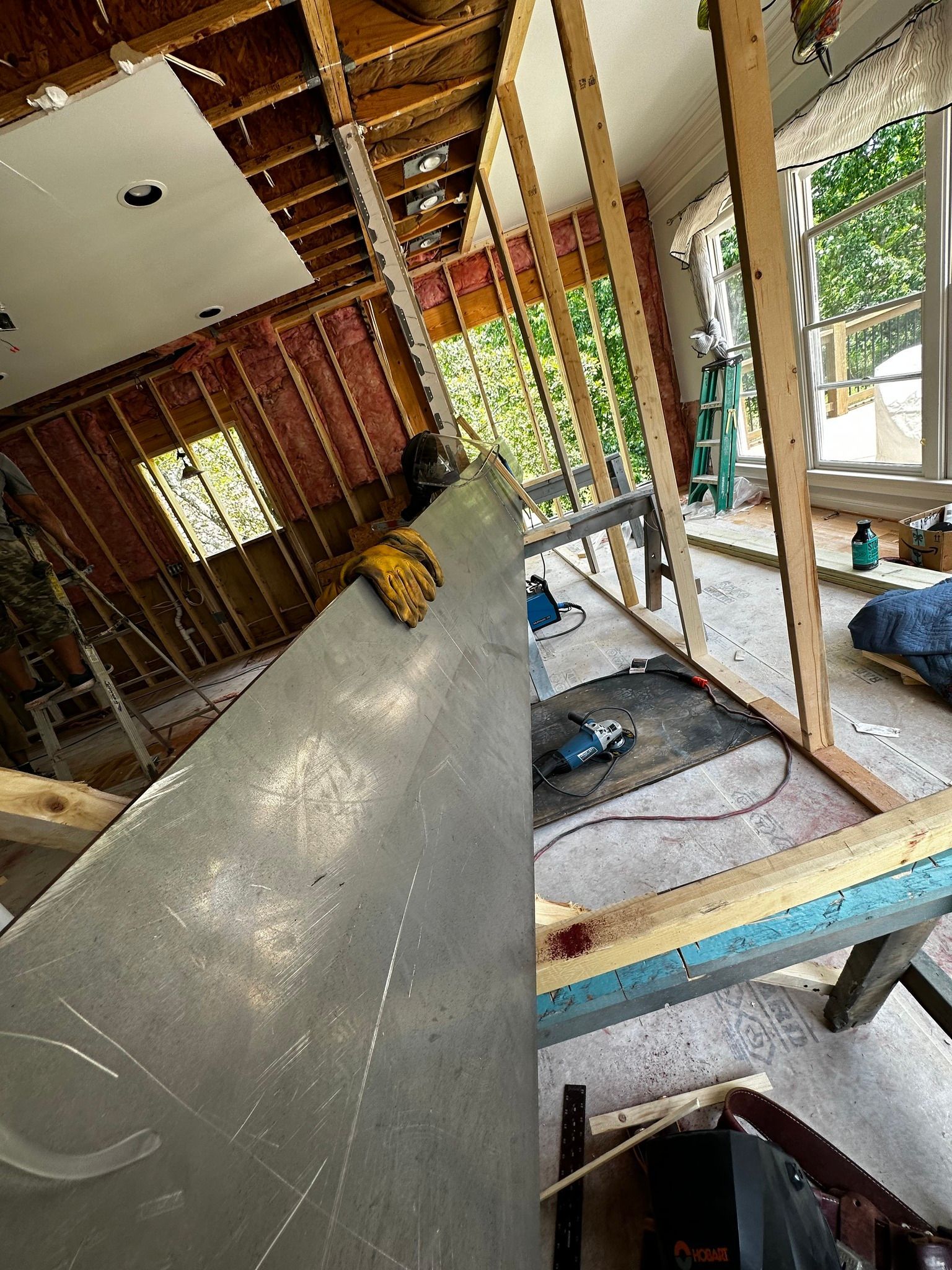 Interior construction: walls framed, drywall partially installed. Saw and tools on concrete.