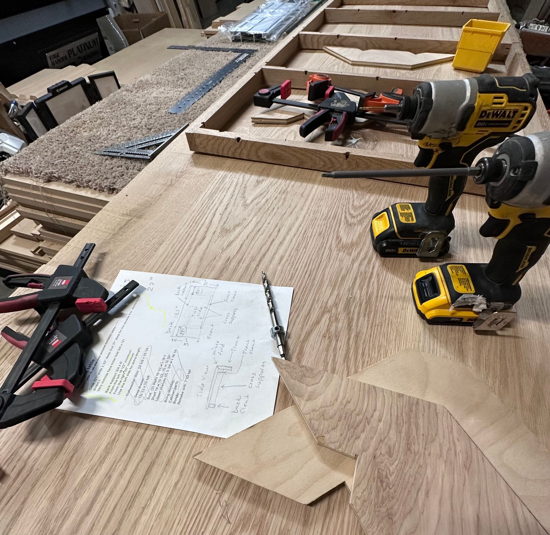 Woodworking project: drills, clamps, and plans on a light wood table.