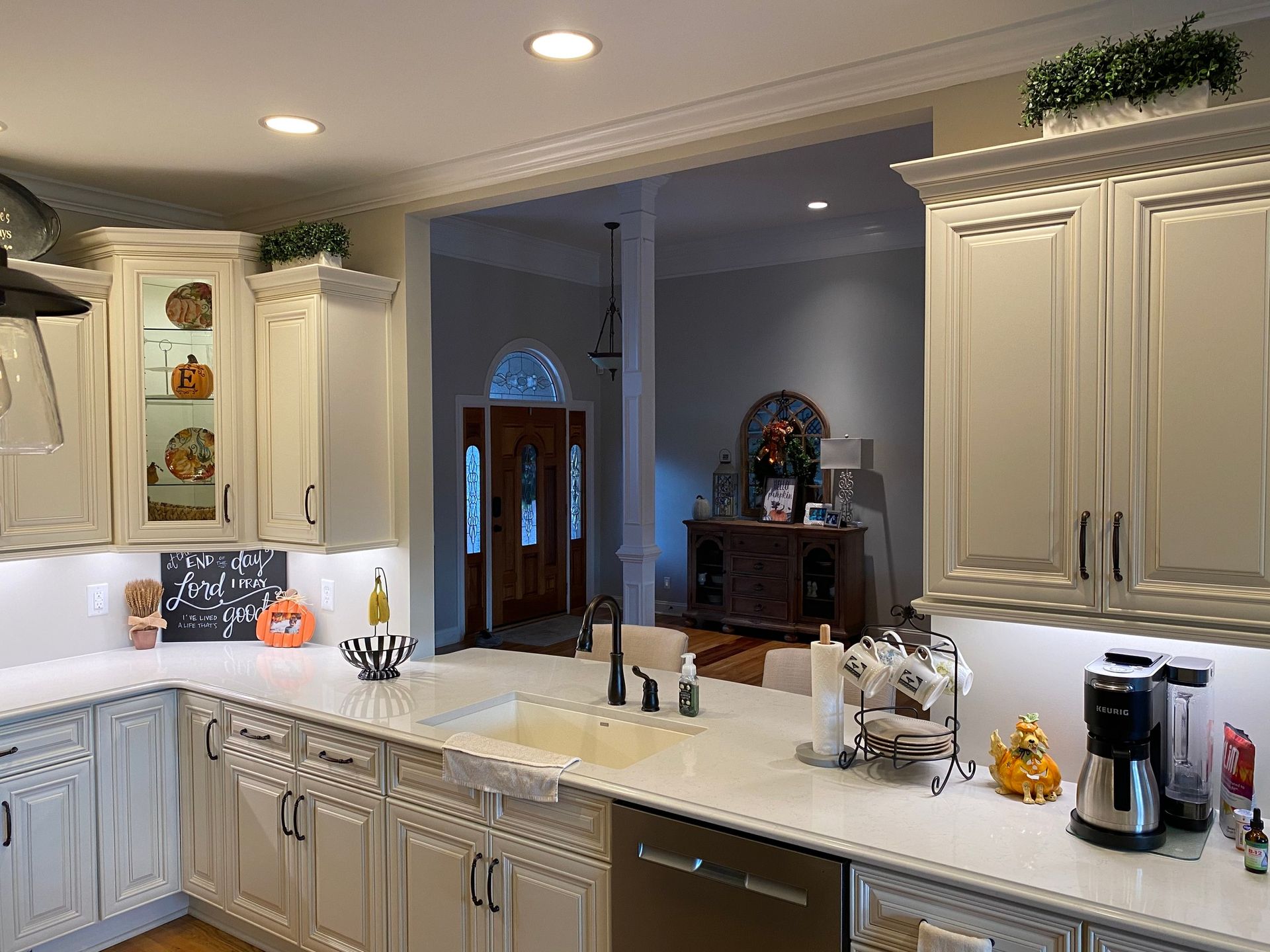 Kitchen with white cabinets, countertops, and sink, with an entryway to the front door.