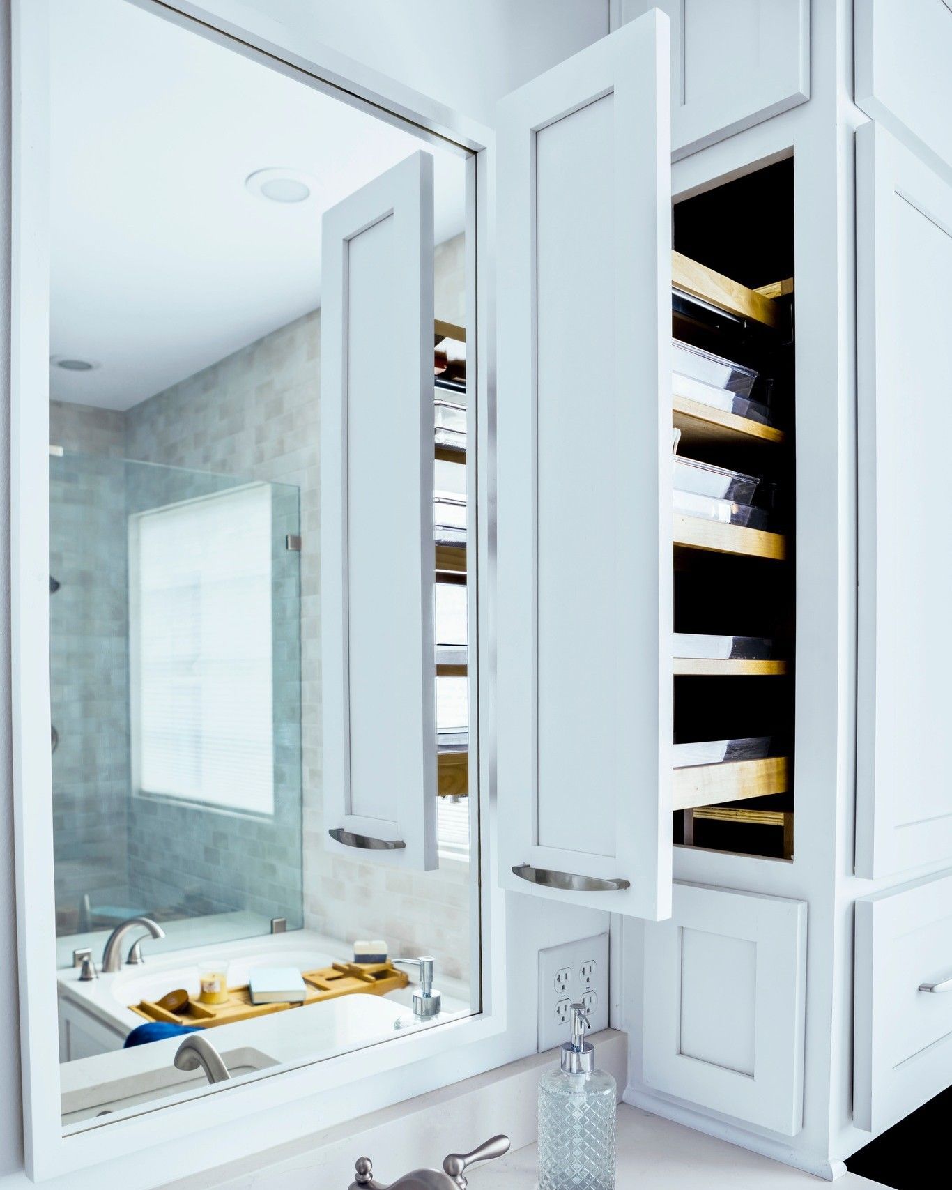 Bathroom cabinet with white doors open, revealing shelves with towels and a mirror reflecting the sink and shower.