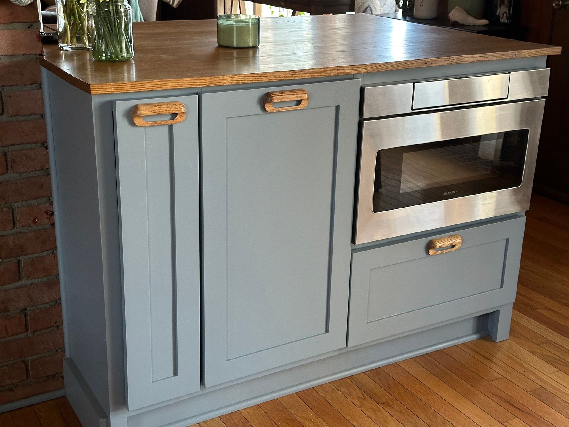 Kitchen island with a blue cabinet, wood countertop, and a built-in microwave.