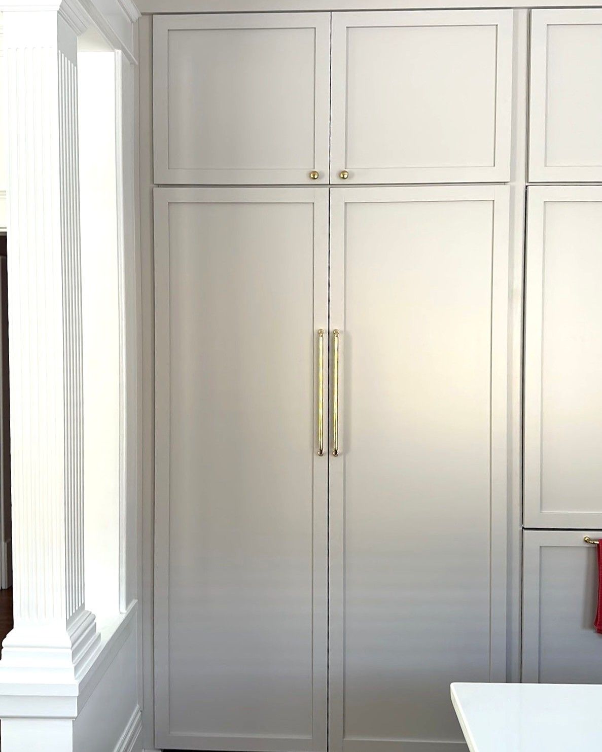 White kitchen cabinets with brass handles and frame detail.