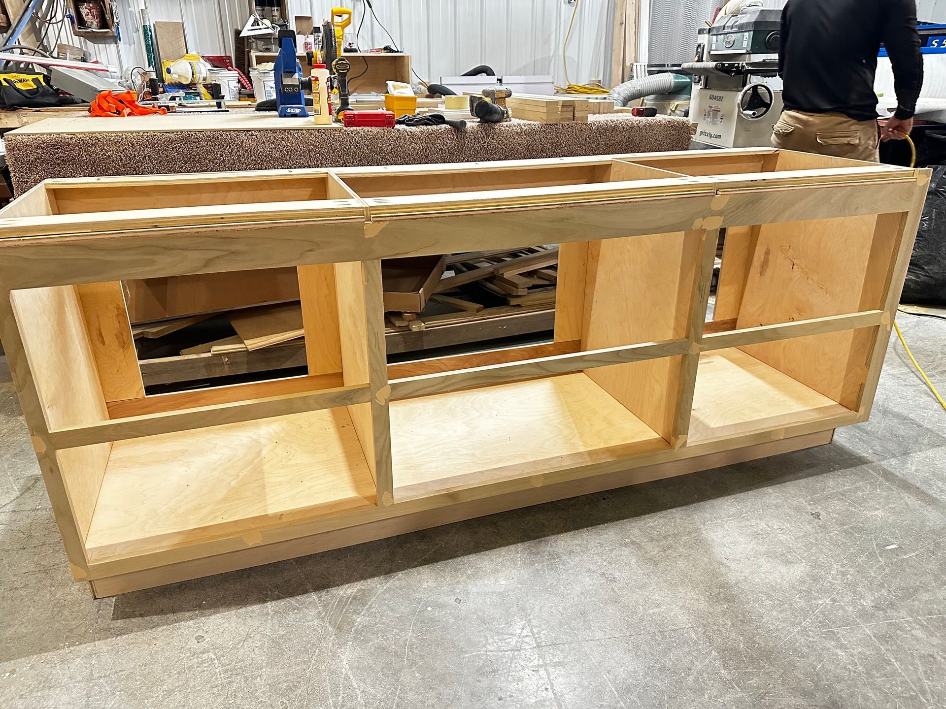 Wooden cabinet frame under construction in a workshop setting.
