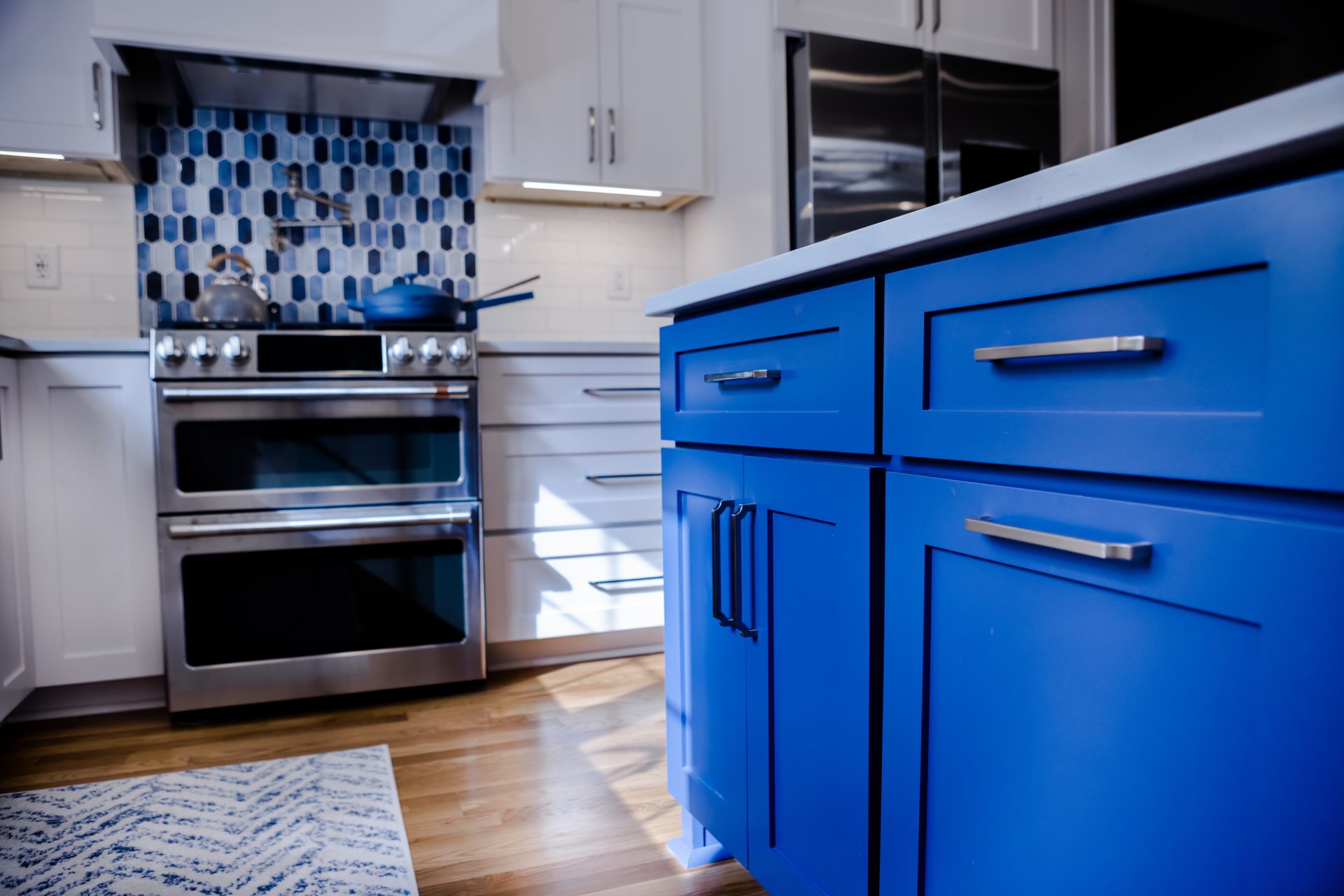 Blue kitchen cabinets with silver hardware in a bright, modern kitchen.