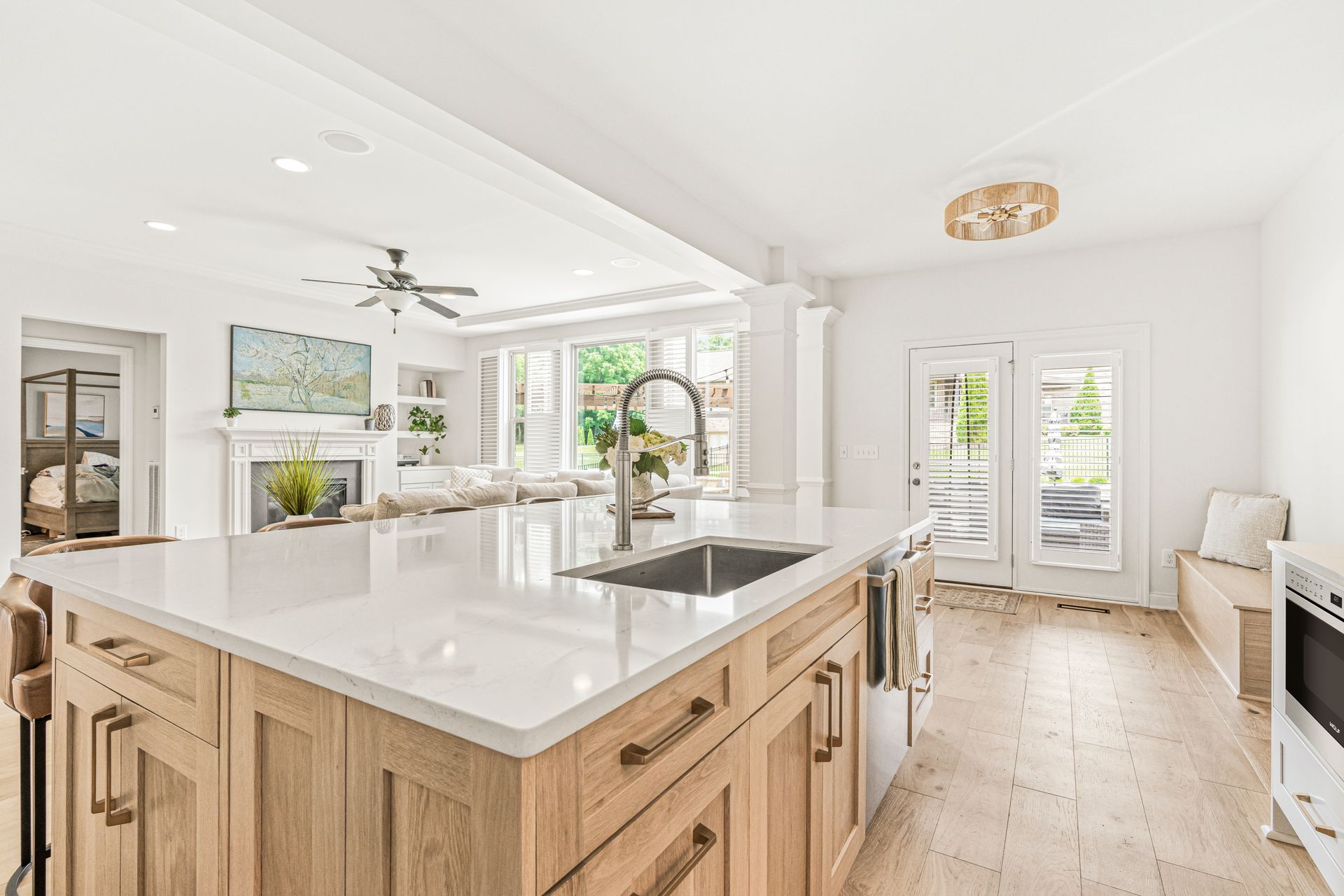 Bright, modern kitchen with light wood cabinets, white countertops, and view of the backyard through French doors.