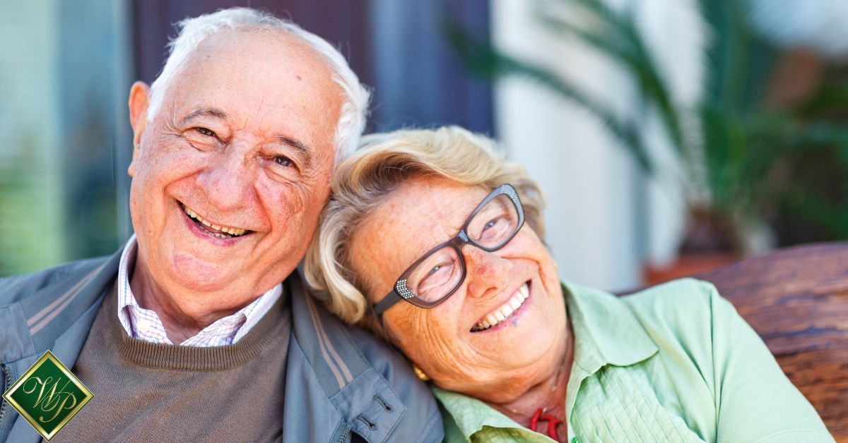 elderly man and woman sitting together smiling - Whispering Pines assisted living near