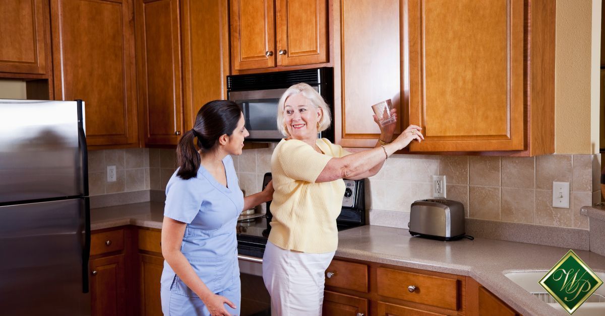 health aide wearing blue scrubs assisting elderly woman grab a glass - Whispering Pines home health aide