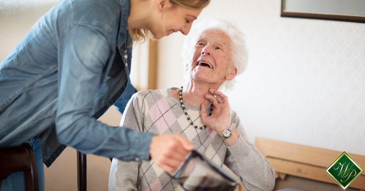 Young man assisting an elderly woman in a bright room, both smiling warmly.