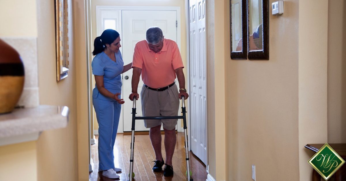 Caregiver assisting an elderly man with a walker in a hallway