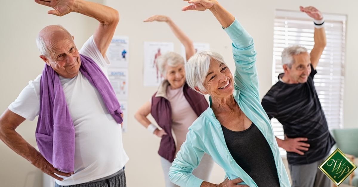 People stretching in a bright exercise class, reaching sideways with arms raised.